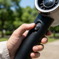 Person holding the compact handheld fan outdoors on a sunny day