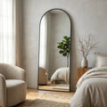 Arched full-length floor mirror in bedroom