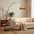 Arc floor lamp with warm dome shade arching over a sofa in a cozy modern living room