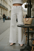 Model wearing white wide-leg jeans at a Paris cafe