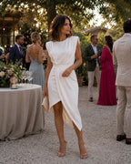 White sleeveless asymmetric polyester dress with draped skirt and padded shoulders.